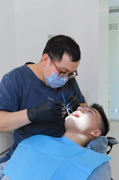 A dentist in a clinic performing a routine checkup on a patient in a dental chair.